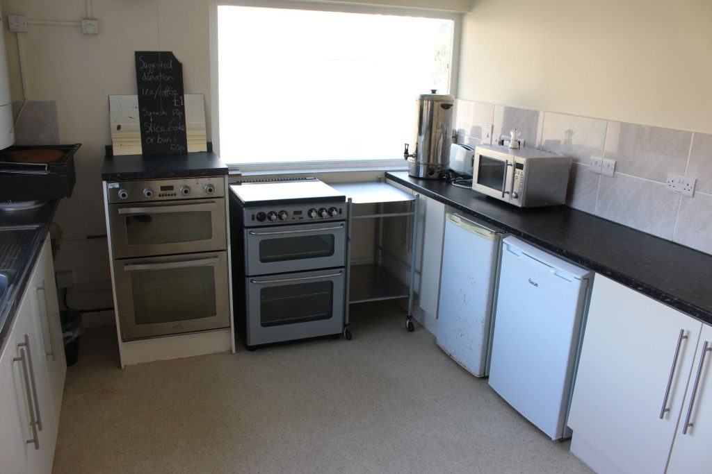 Kitchen showing 2 ovens, microwave, fridge, freezer and urn.